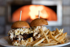 Sliders with mac n cheese and french fries in front of wood fired oven