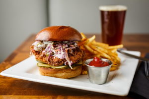 fried chicken sandwich on platter with fries and beer