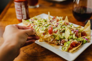 plate of tortilla chips with ahi tuna and sauce on table with glass of wine